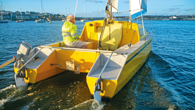 A man in a yellow coat sailing a Chat 18 catamaran