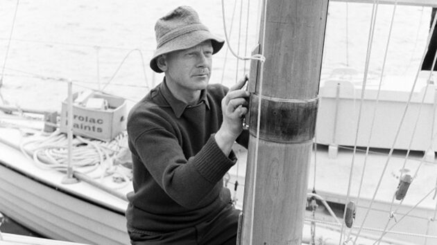 A sailor adjusting lines at the mast