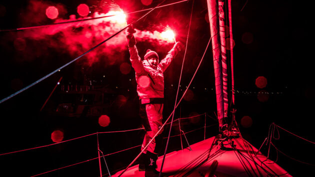 Pip Hare holding a flare on her boat after finishing the Vendee Globe yacht race