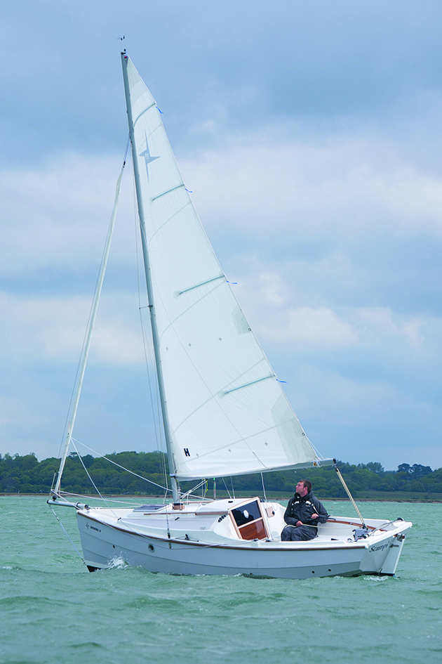 A man sailing a boat with white sails