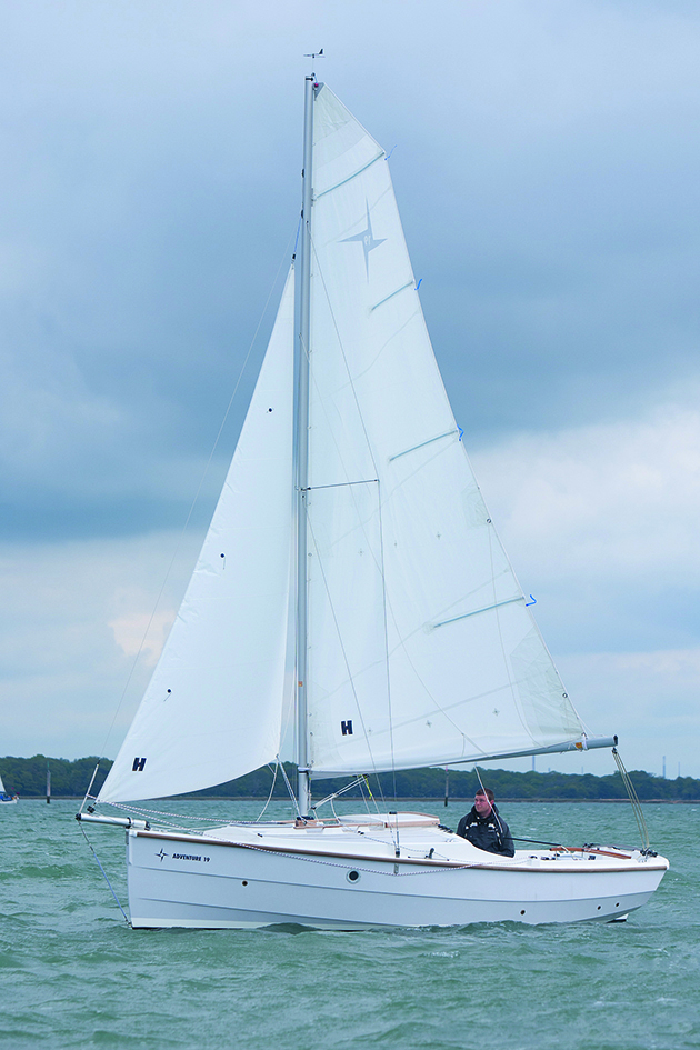 A man sailing a boat with a white hull and white sails