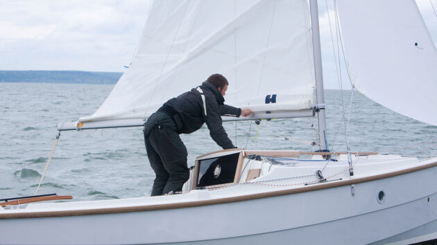 A man reefing a sail on a boat