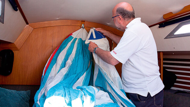A man handling a sail in the cabin of a boat