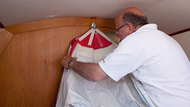 A man packing a spinnaker sail on a boat