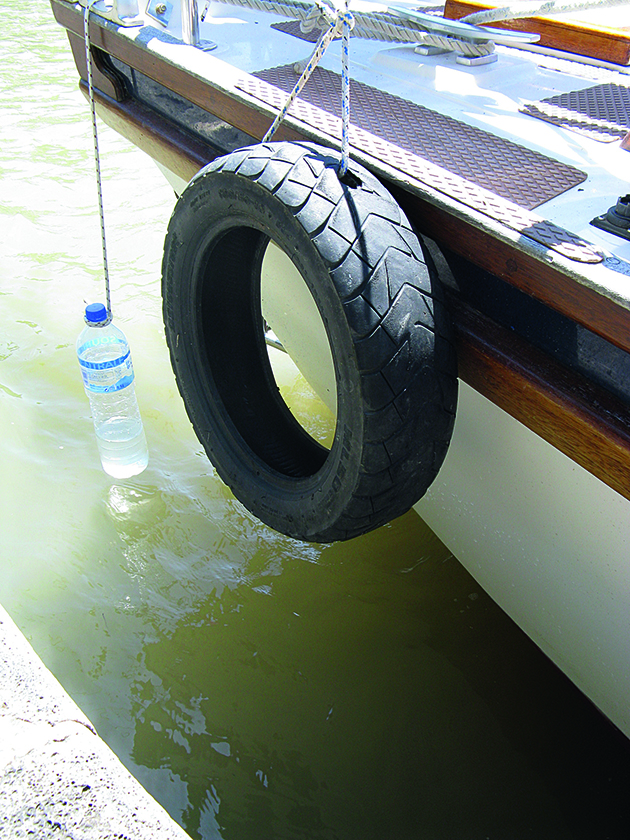 A half filled mineral water bottle being used as a fender on a boat