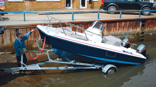 A man launching a boat from a break-back trailer on a slipway