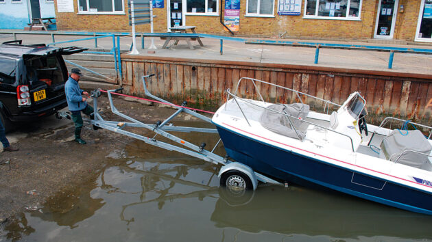 A man recovering a boat from the water with a trailer