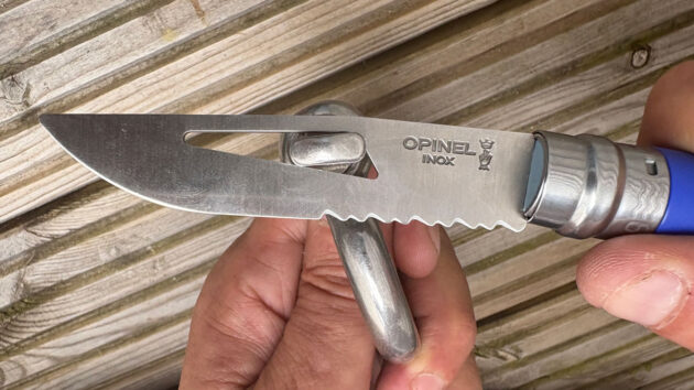 A man undoing a shackle with a shackle key integrated into a sailing knife