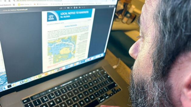 A man looking at a laptop to learning about racing dinghies and racing movements