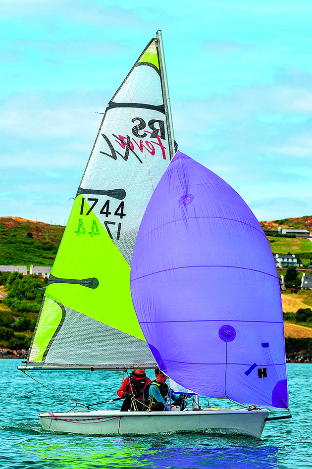 Crew on a racing dinghy sailing with a spinnaker