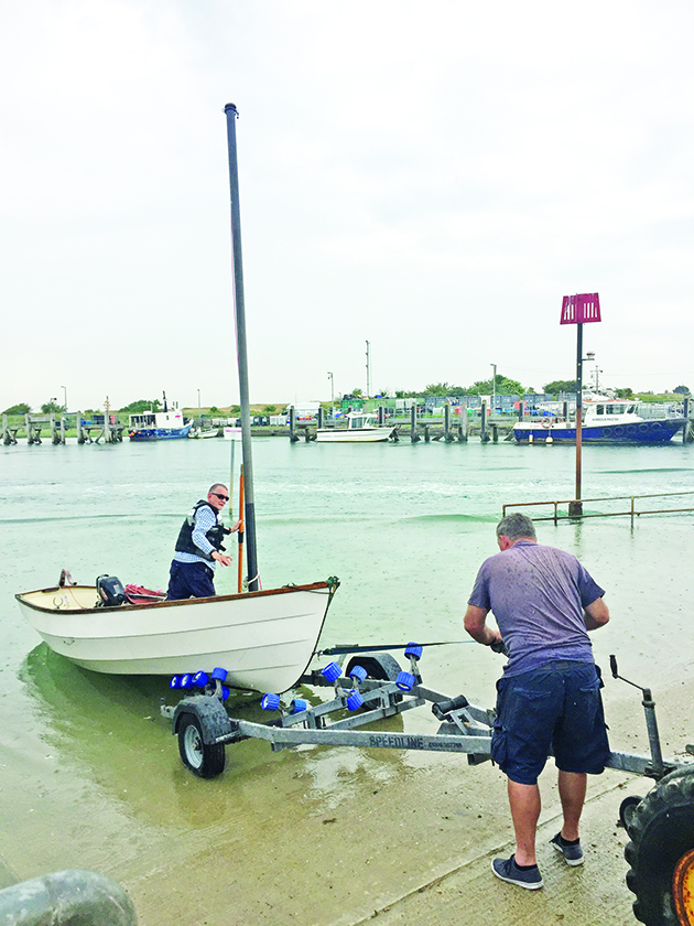 Two men launching a dinghy from a slipway