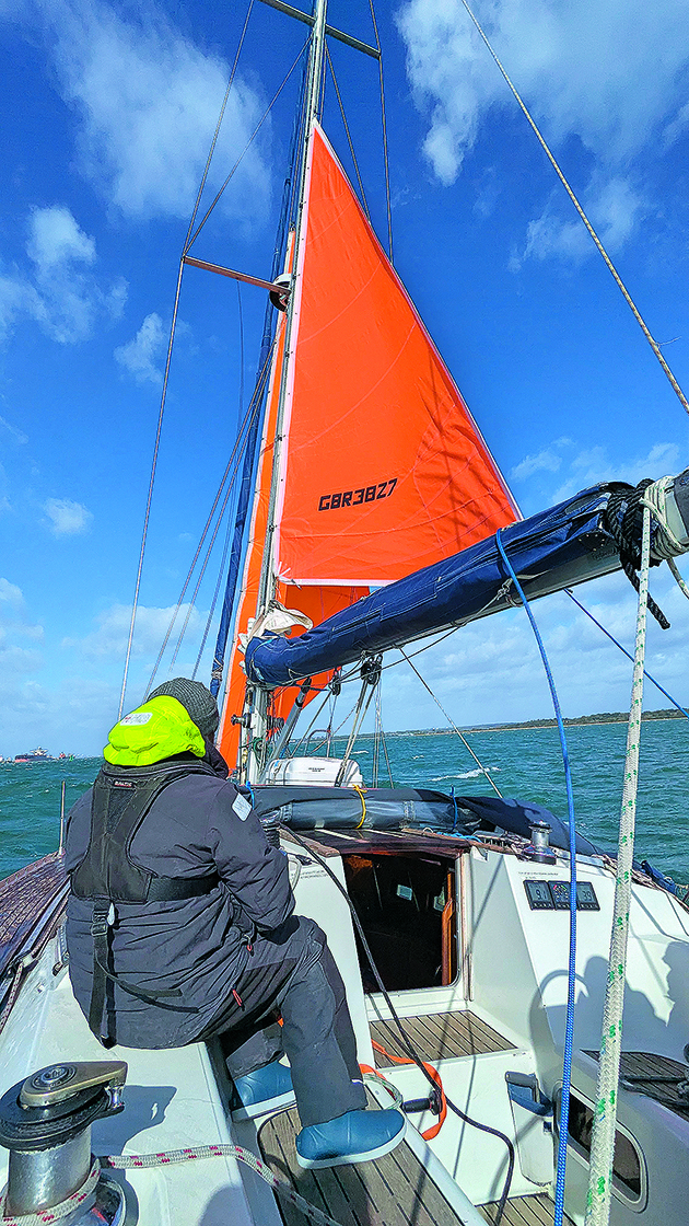 Two people on a boat preparing to gybe