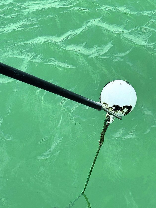 A boat hook being used to pick up a mooring buoy for a boat