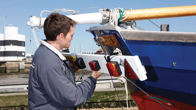 A man fixing a number plate to the back of a boat for trailering