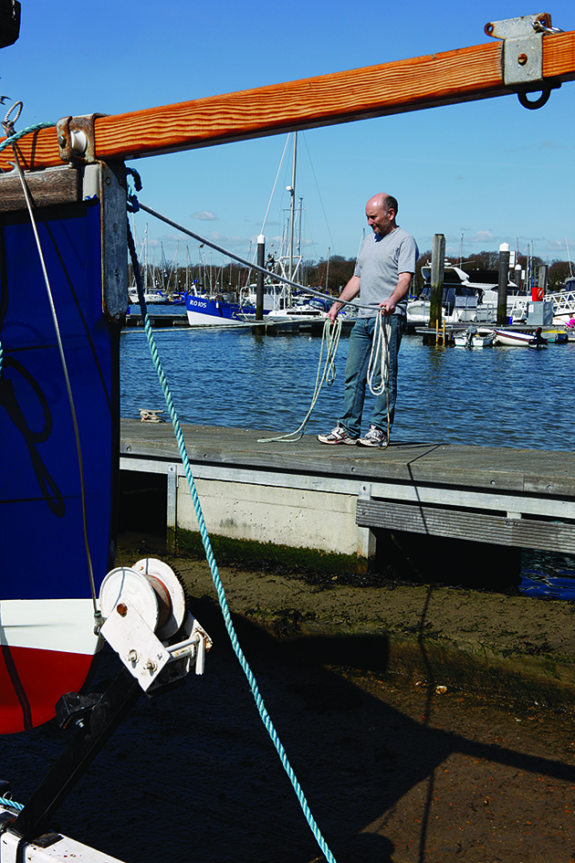 A man standing on a pontoon with rope launching a boat