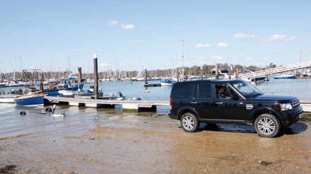 A van being reversed down a slipway to recover a boat