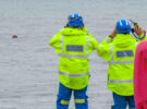 An HM Coastguard search and rescue team keeping watch on a large wooden cable reel floating 100 meters off the beach at Burton Bradstock, Dorset. Credit: Graham Hunt/Alamy