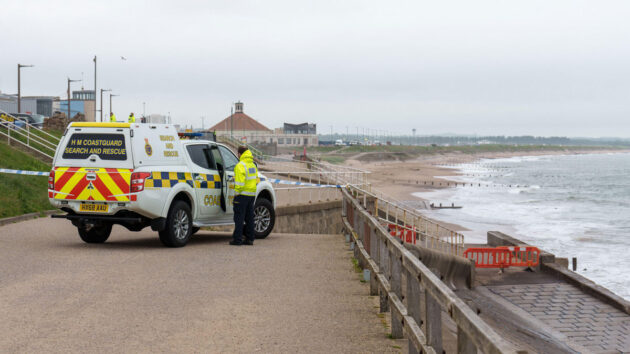 Coastguard vehicle and officer stand on Aberdeen Beach Esplanade. A cordon blocks access to the beach and water due to a suspected unexploded bomb. Credit: JASPERIMAGE/Alamy Live News