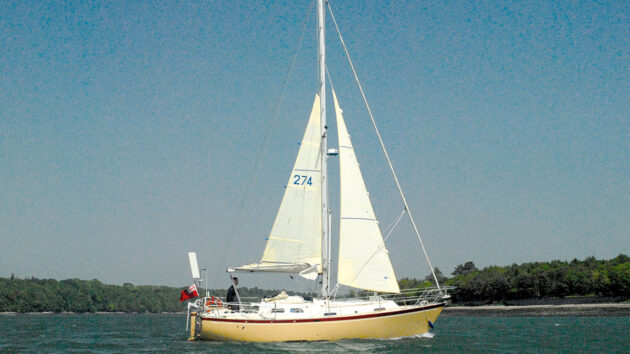 A yacht with white sails and cream hull sailing