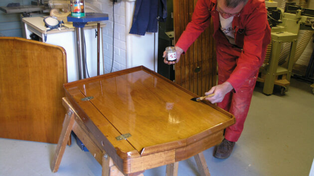 A man marine varnishing a chart table for a yacht