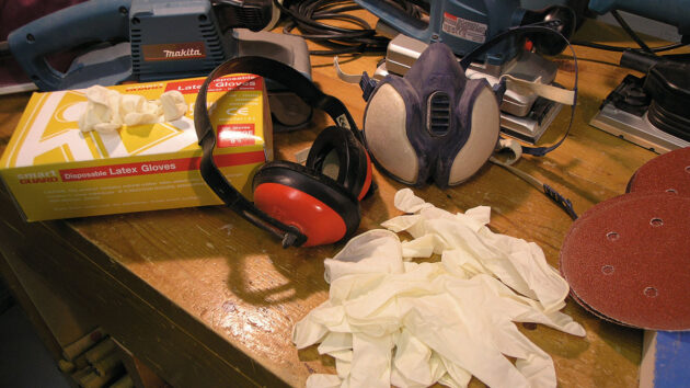 Latex gloves and ear defenders on a workbench used for marine varnishing on a boat