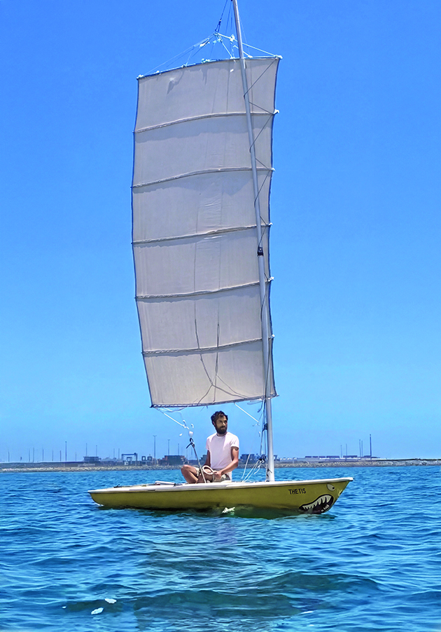 A man sailing a Laser dinghy with DIY sails