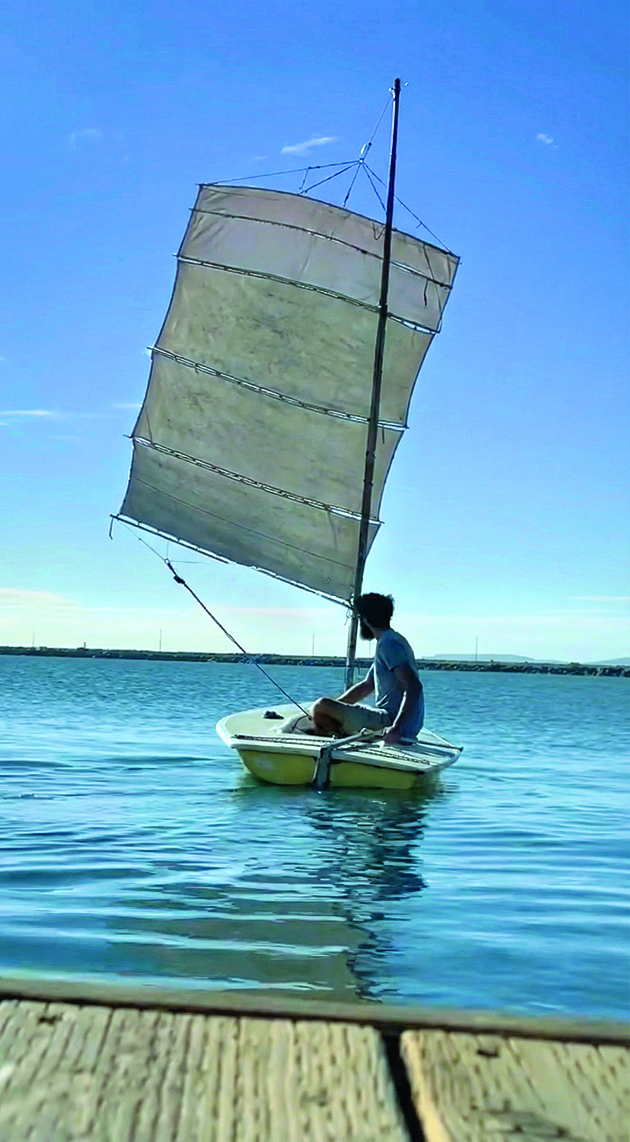 A man sailing a laser dinghy with DIY sails