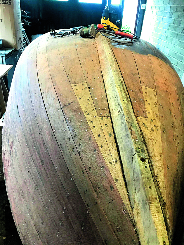 An upturned hull of a wooden dinghy in a workshop