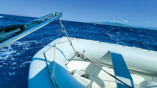 A PVC dinghy raised off the back of a boat