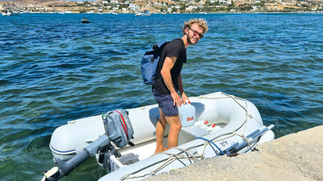 A man in a black tshirt and blue shorts standing in an inflatable PVC dinghy
