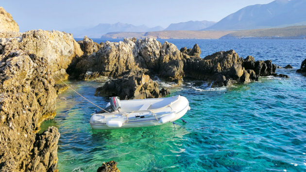 A PVC inflatable dinghy anchored off some rocks in Greece