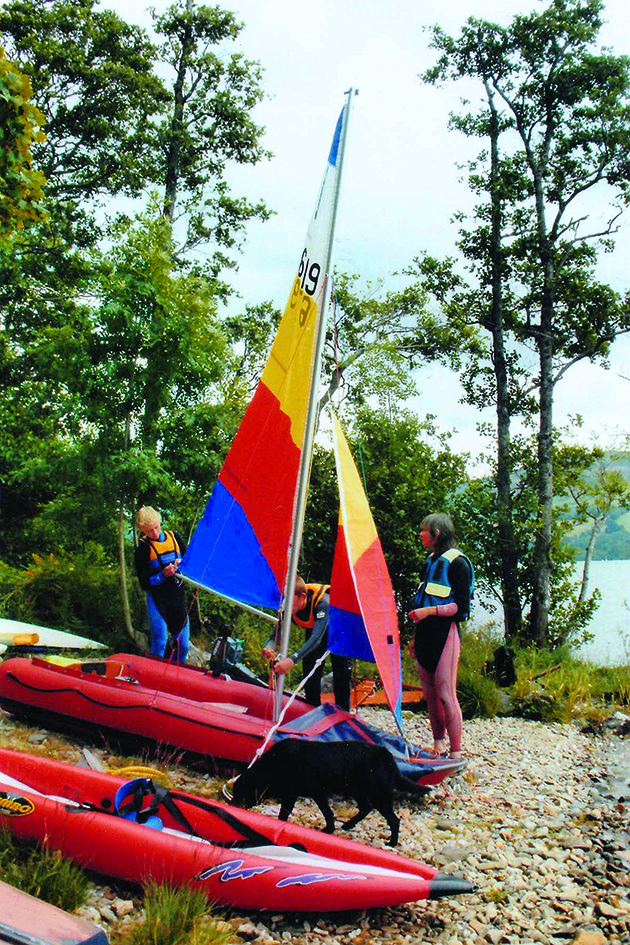 Two people manoeuvring a Tinker dinghy on the shore