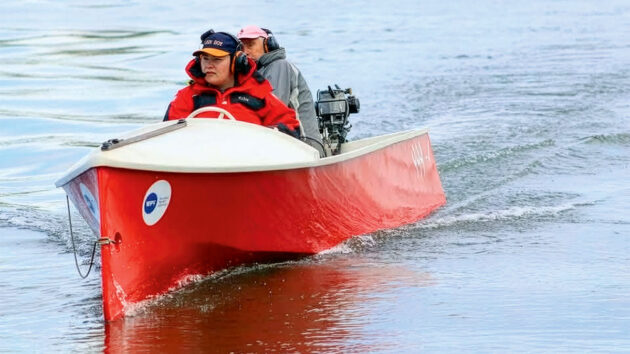 Two people in a small boat powered by a Seagull outboard engine