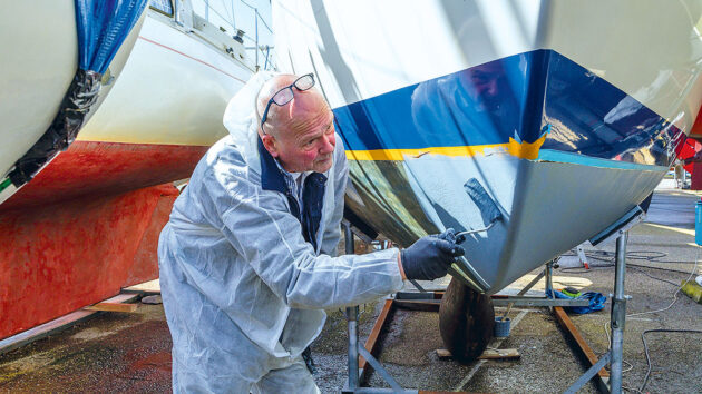 A man applying antifouling paint to a boat