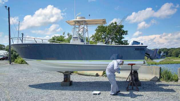 A man using antifouling paint to paint a boat