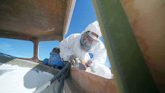 A person working full personal protection equipment working on a boat
