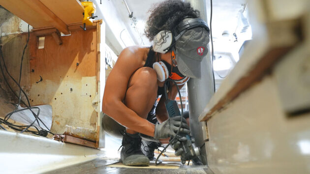 A woman using a power tool to make changes to a yacht