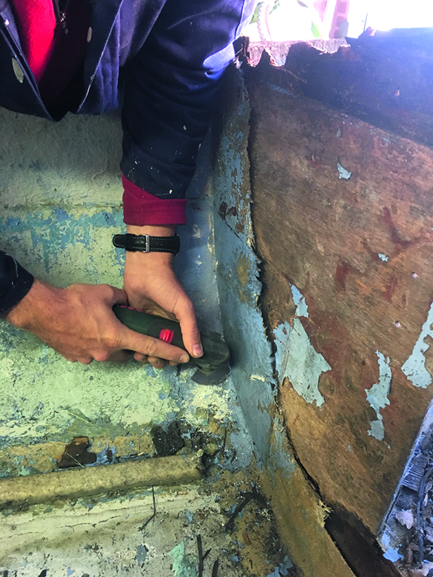 A man using a cutting tool to make dinghy repairs