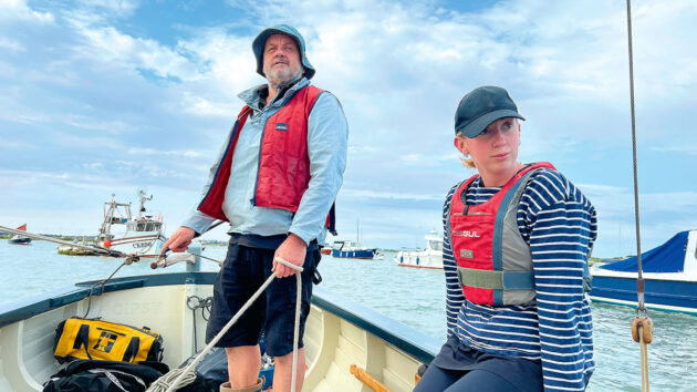 Two people steering a tiller-steered boat