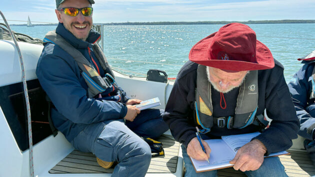 Sir Robin Knox-Johnston signing a log book