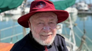 Sir Robin Knox-Johnston wearing a red hat while sailing