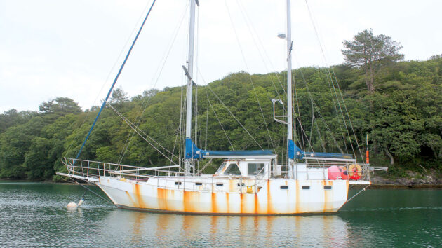 A metal yacht with rust streaks on the hull moored