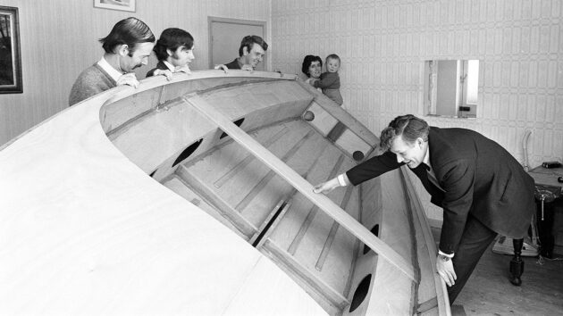 A family moving a plywood yacht after it was built in a living room
