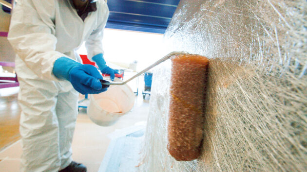 A man using chopped strand mat as part of boat construction