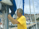 A man trying to feed a reefing line back into a boom on a boat