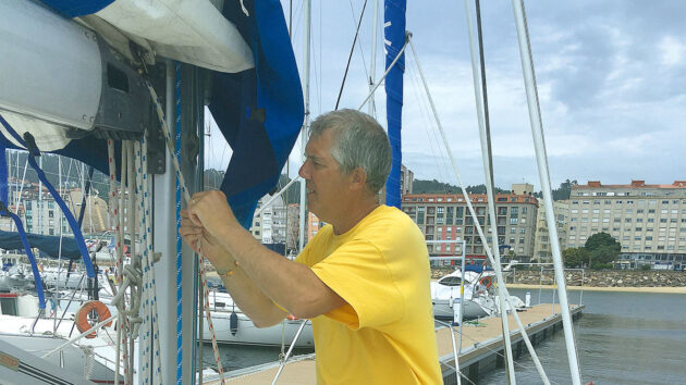 A man trying to feed a reefing line back into a boom on a boat