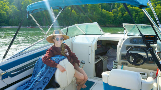 a woman smiling while sitting in the cockpit of a motorboat