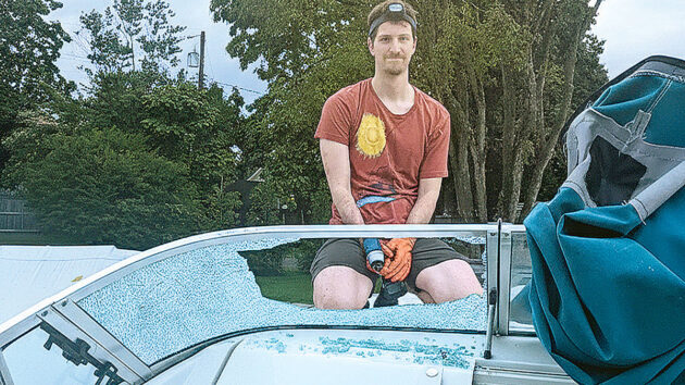 A man removing a shattered boat windscreen