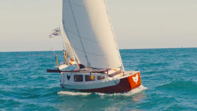 A small boat with a red hull and white sails