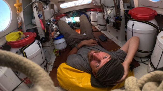 Yann Quenet lying down in his 4m boat